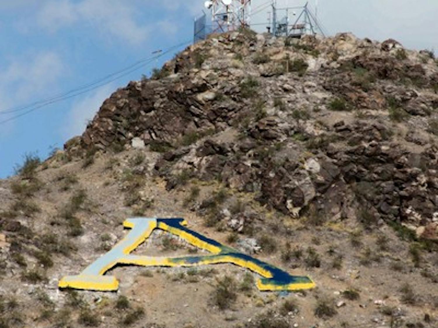 The "A" on Hayden Butte was painted white and blue following ASU's loss to the University of Arizona Saturday night. The ten ASU students and alumni who repainted the "A" gold Monday afternoon said they suspected it was painted by U of A students Sunday night during the rainstorm. (Photo by Lisa Bartoli)