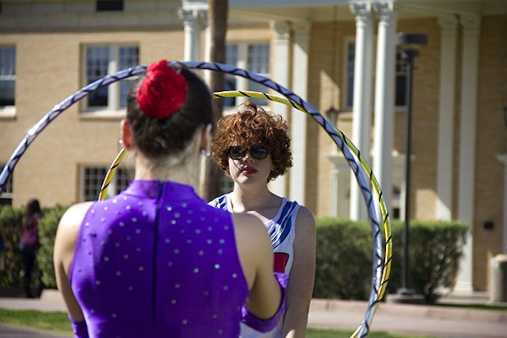 Circus performer Mary Adrenaline teaches ASU sophomore earth and space exploration major Bridget Russell how to hoop on Hayden Lawn. The Arizona Circus School performed on the Tempe campus today with Project Humanities. (Photo by Diana Lustig)