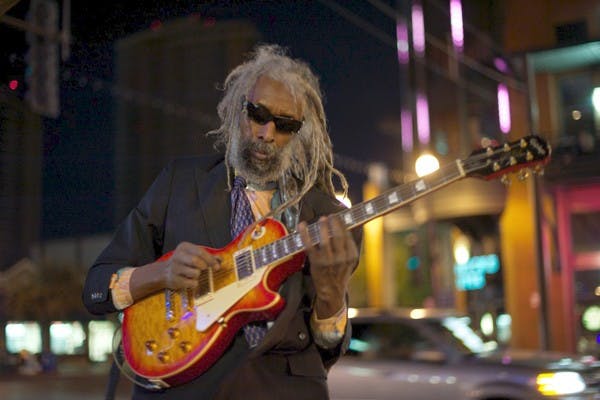 LATE NIGHT SHREDDER: "Bing," an electric guitarist now several months unemployed, performs for donations at the intersection of Mill Avenue and Fifth Street. Raised by musician-parents, Bing was forced to learn music from an early age. He now plays more than 5 instruments to support his income. (Photo by MIchael Arellano)