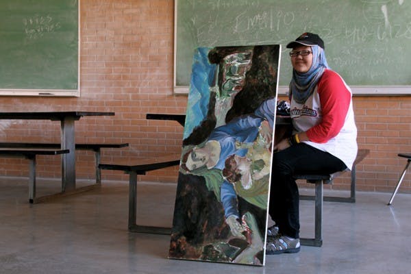 LADY IN PAINTING: Painting senior Kadhima Tung waits between classes with her latest piece of art outside of the Physical Sciences Center Oct. 26. (Photo by Rosie Gochnour)