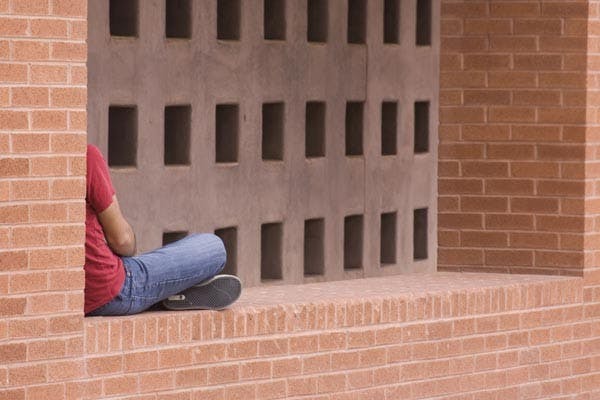 BREAK FROM CAMPUS: A student relaxes in the arches of the Nelson Fine Arts Center between classes Monday afternoon. (Photo by Annie Wechter)