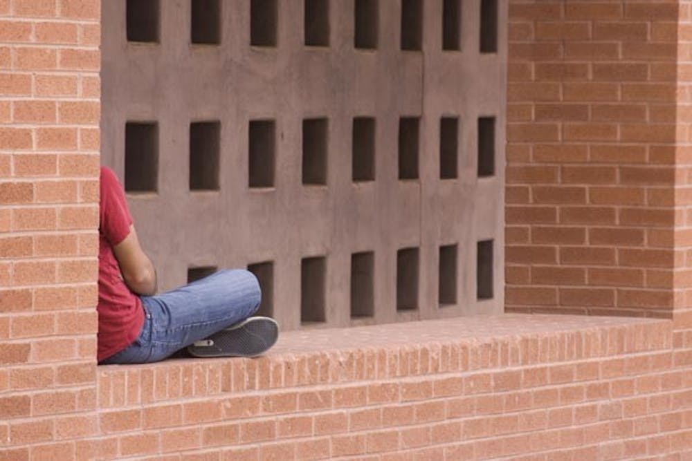 BREAK FROM CAMPUS: A student relaxes in the arches of the Nelson Fine Arts Center between classes Monday afternoon. (Photo by Annie Wechter)