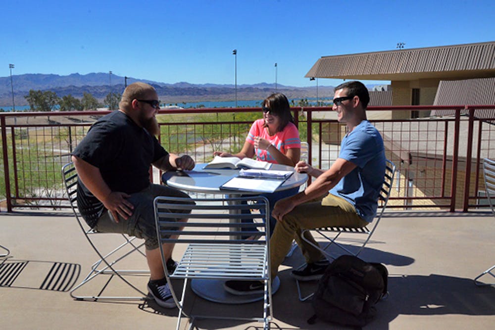 Life Sciences majors, juniors, (left) Tom Bullock and Shelby Verhyen take advantage of Havasu's phenomenal cool weather by socializing in-between classes with, organization leadership major, Kennan Espy (right), on the student center's patio. (Photo by Rachel Nemeh)
