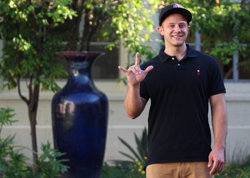 Ted Horton-Billiard poses with his favorite sign, the universal sign of love in ASU's Secret Garden. Billiard, who is currently rushing to be in a fraternity, is a deaf student who lives on the Tempe campus, where he studies history. (Photo by Dominic Valente)