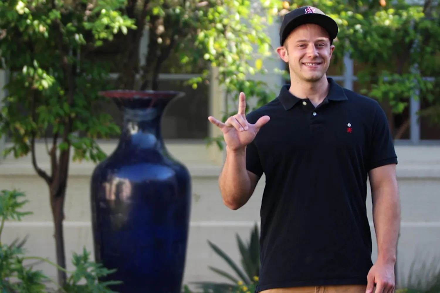 Ted Horton-Billiard poses with his favorite sign, the universal sign of love in ASU's Secret Garden. Billiard, who is currently rushing to be in a fraternity, is a deaf student who lives on the Tempe campus, where he studies history. (Photo by Dominic Valente)