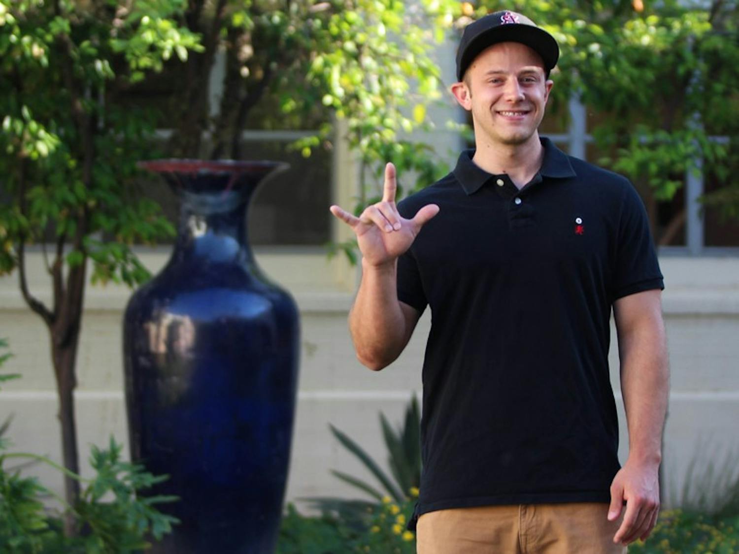 Ted Horton-Billiard poses with his favorite sign, the universal sign of love in ASU's Secret Garden. Billiard, who is currently rushing to be in a fraternity, is a deaf student who lives on the Tempe campus, where he studies history. (Photo by Dominic Valente)