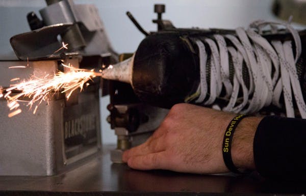 Before each game the equipment manager John Peters sharpens the team’s skates.  (Photo by Ana Ramirez)
