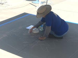 Lisa Bernal Brethour, photographed on Sept. 24,&nbsp;begins her most recent street mural with an outline of the most detailed parts of the piece. Brethour uses soft pastels to create her street art, and often uses water to help the pigment stick to tough pavement.