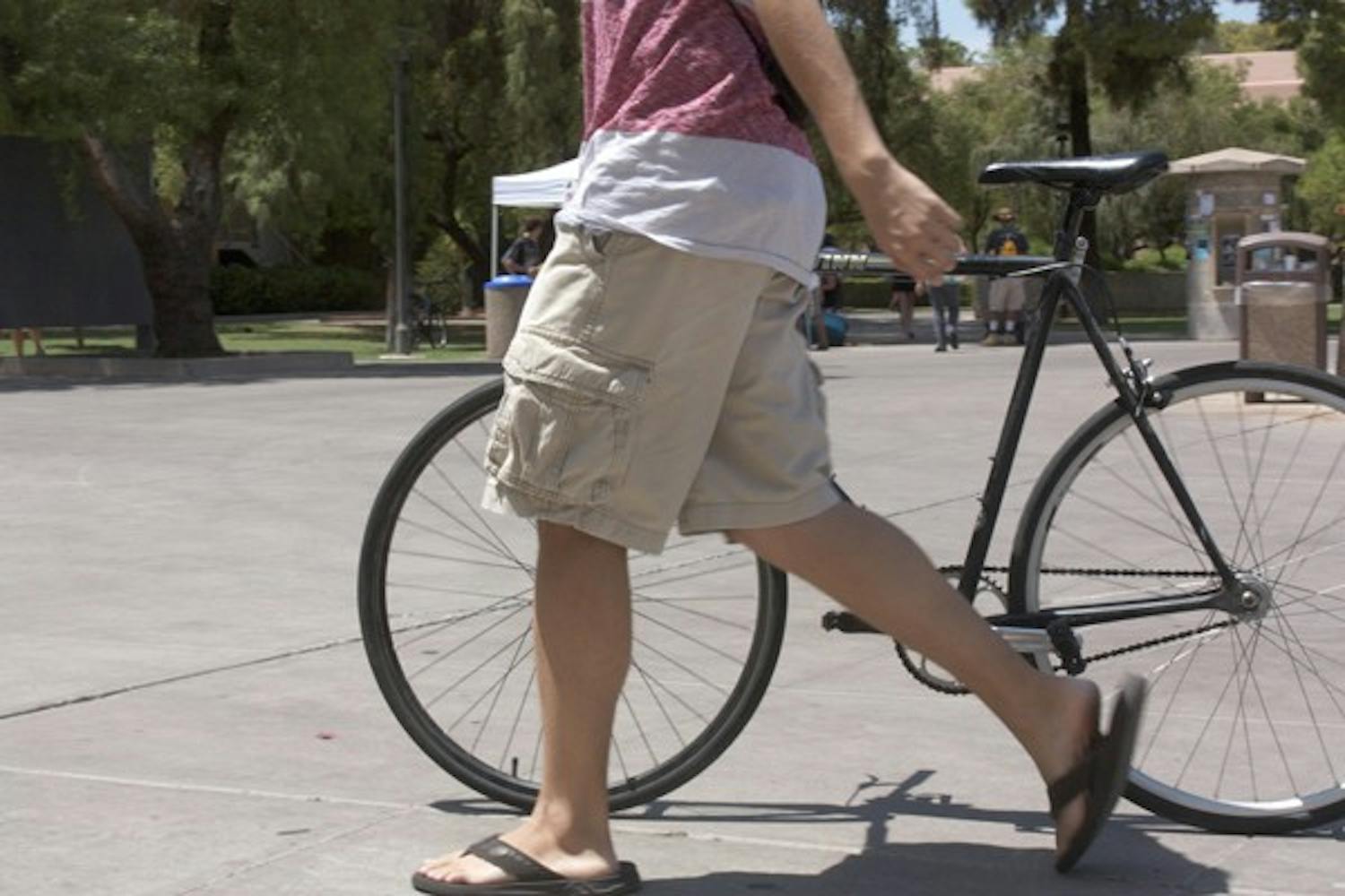 A student walks his bike through the Tempe campus.  A new campaign "Walk Your Wheels" encourages students to walk rather than ride bikes and skateboards through crowded areas on campus. (Photo by Shawn Raymundo)