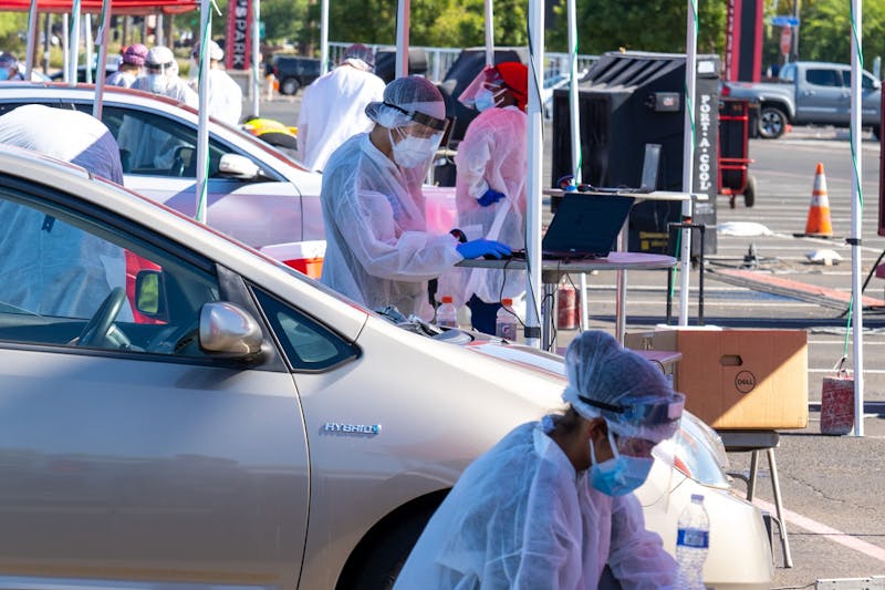 Volunteers collect test tubes from people who have completed the ASU Biodesign saliva test on Tuesday, July 28, 2020, outside State Farm Stadium in Glendale. 