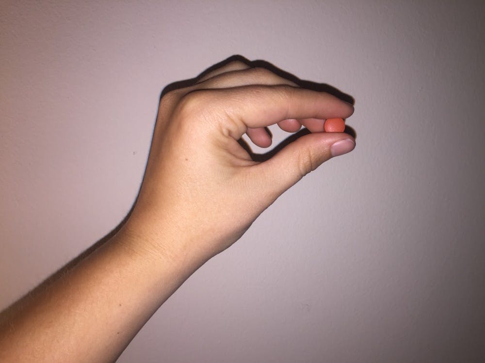 Photo illustration of a student holding&nbsp;a pill on April 25, 2017.