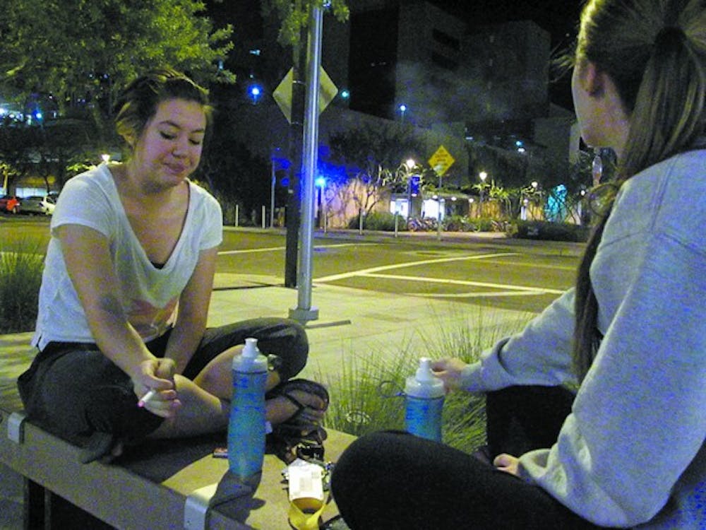Freshmen Katie Scheetz and Amy Mogensen enjoy a late-night cigarette outside of Taylor Place. (Photo by Tyler Griffin)