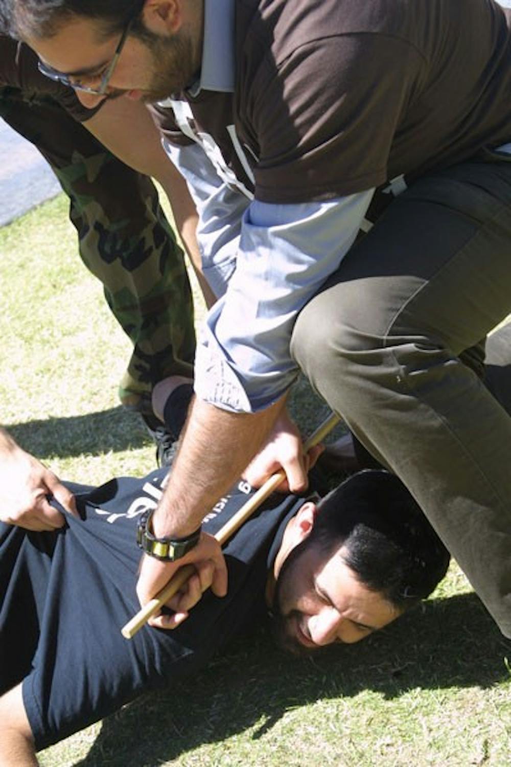 JUSTICE IN PALESTINE: A member of the Students for Justice in Palestine is wrestled to the ground by the other members depicting the violence faced by Palestinians by Israeli soldiers at the West Bank checkpoints each day. The event which took place on Hayden lawn Wednesday afternoon was to bring awareness to plight of the Palestinian. (Photo by Serwaa Adu-Tutu)