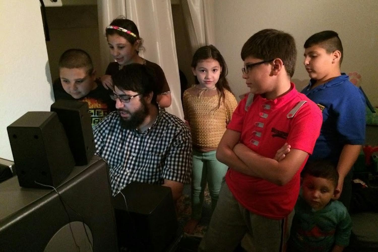 Riad Sbai, ASU alum and founder and president of PCs for Refugees, shows a family how to use new programs on their donated computer.