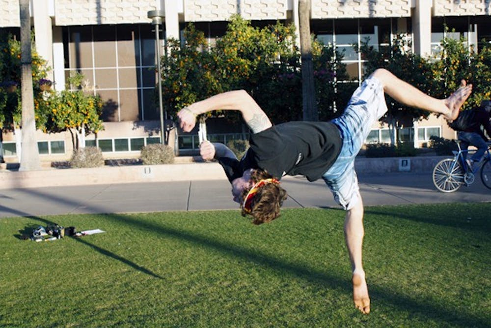 Tyler Bevier, a freshman psychology student, does a flip on Hayden Lawn on a sunny Arizona afternoon. (Photo by Cameron Tattle)