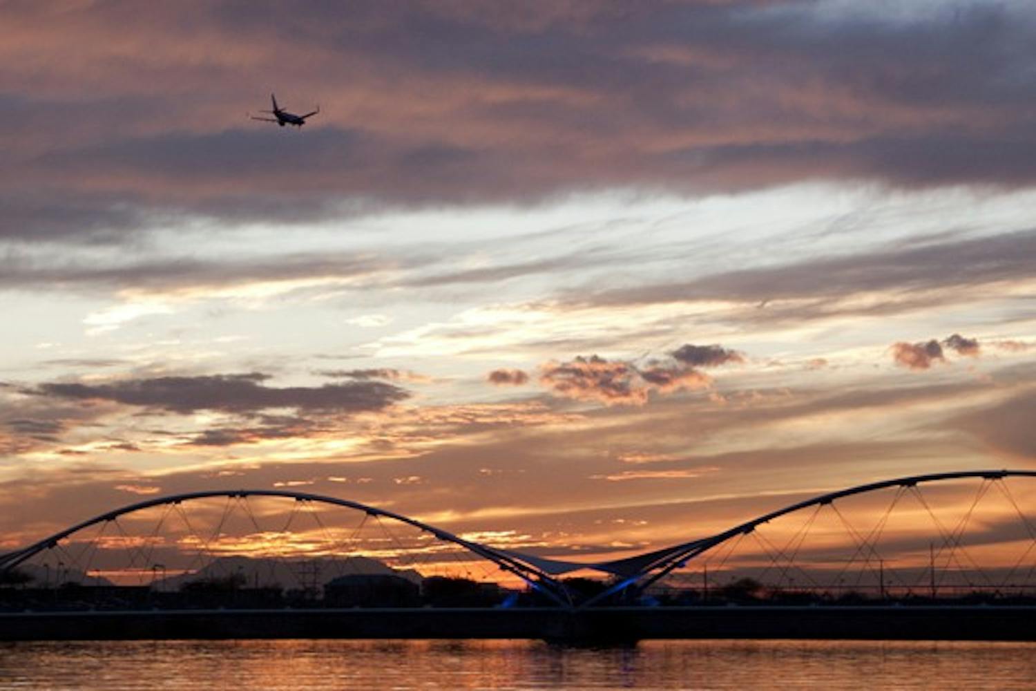 A plane flies over Tempe Town Lake towards Sky Harbor as the sun sets. The Tempe City Council has been dealing with noise complaints from air traffic. (Photo by Abhiram Chandrashekar)