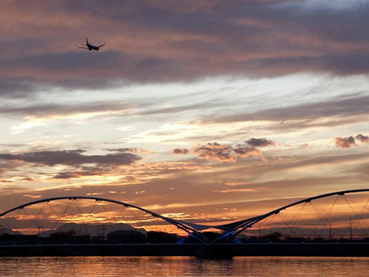A plane flies over Tempe Town Lake towards Sky Harbor as the sun sets. The Tempe City Council has been dealing with noise complaints from air traffic. (Photo by Abhiram Chandrashekar)