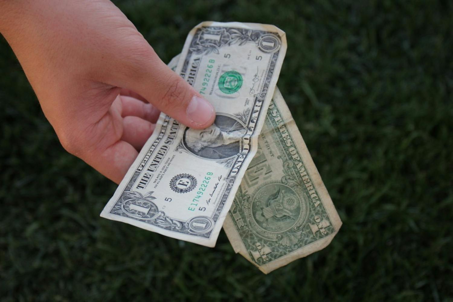 An ASU student holds up two dollars on the Tempe campus on March 12, 2017. 