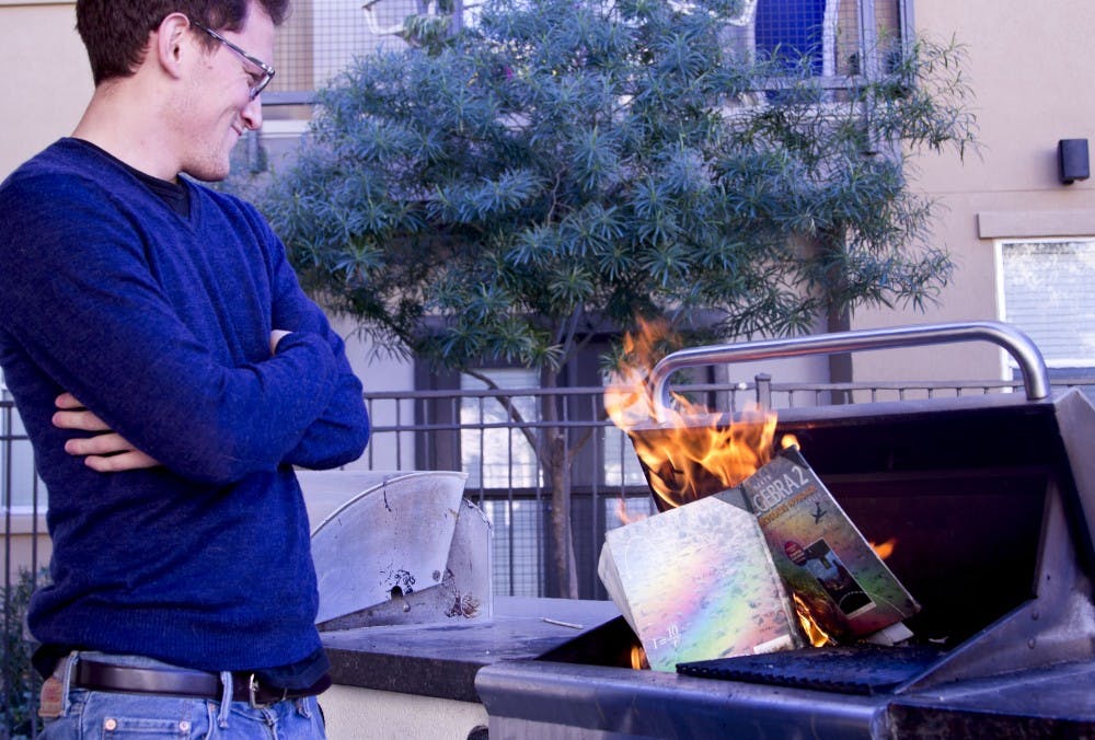 Writer Ryan Espinoza-Marcus cheerfully stands by watching the flame consume an old textbook.
Photo by Ana Ramirez
