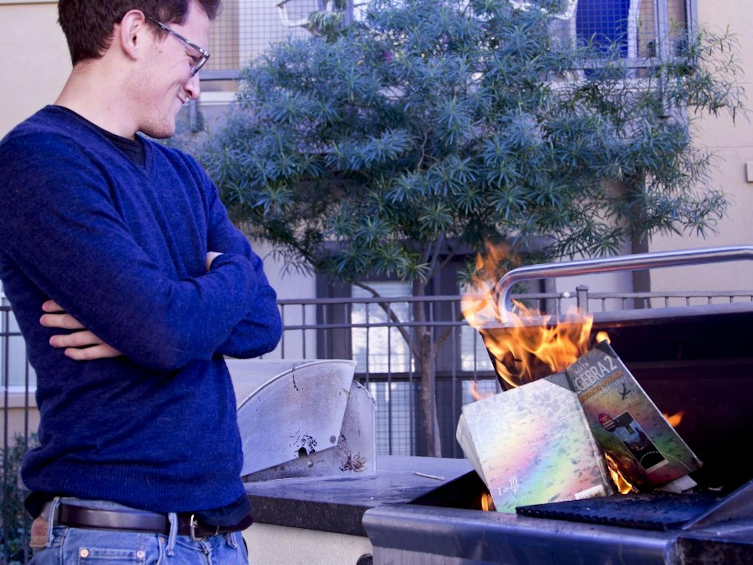 Writer Ryan Espinoza-Marcus cheerfully stands by watching the flame consume an old textbook.
Photo by Ana Ramirez