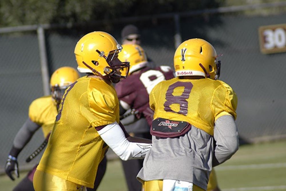 Redshirt senior quarterback Taylor Kelly hands the ball off to junior running back D.J. Foster during an offensive drill at Kajikawa practice field on Dec. 20. ASU plays Duke in the Sun Bowl on Dec. 27. (Photo by: Fabian Ardaya).