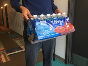 Student holds case of water