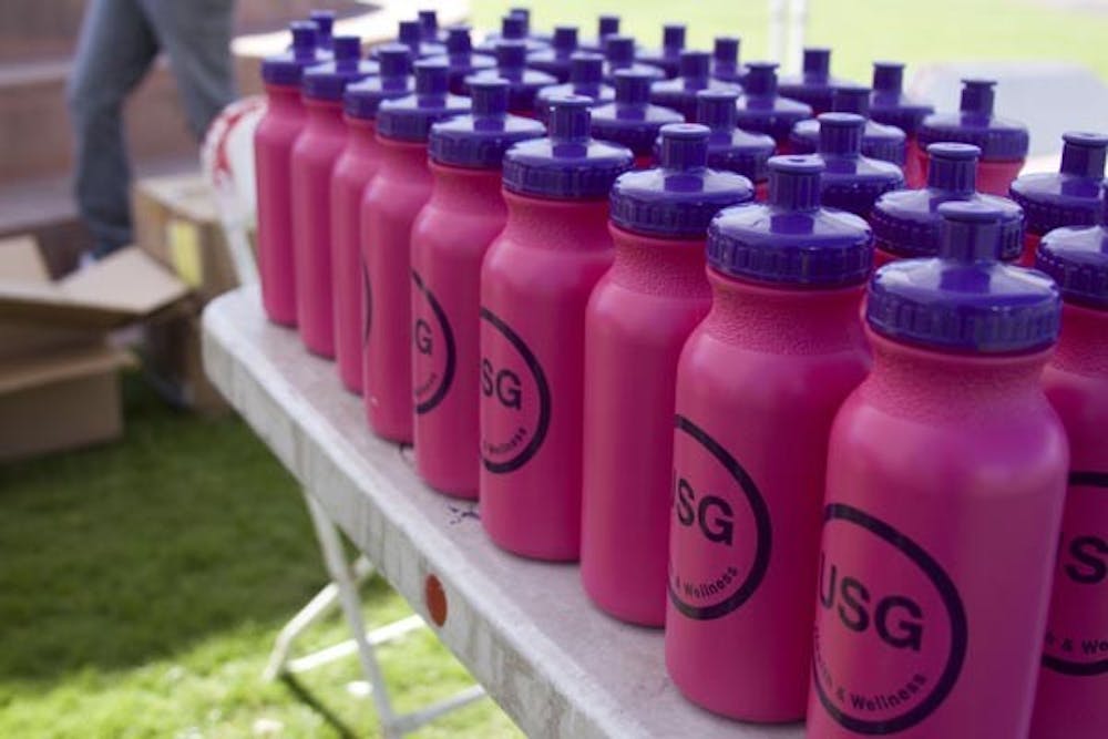 VOTING INCENTIVES: The Undergraduate Student Government handed out free swag such as these water bottles on Hayden Lawn Wednesday to encourage students to vote. (Photo by Annie Wechter)