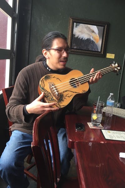 Eduardo Rodriguez describes his ukulele bass guitar on Saturday, Jan. 10, 2014 in Las Cruces, New Mexico. Rodriguez and two other musicians have played together at a local farmer's market for almost two years. (Venessa Santiesteban/The State Press)