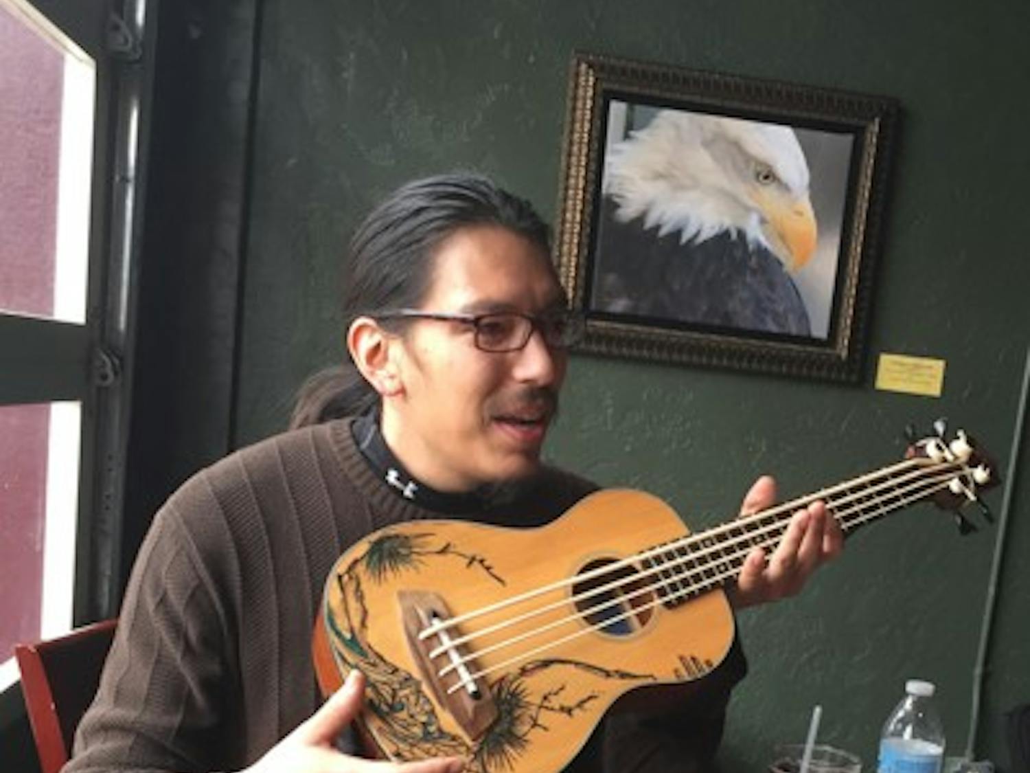 Eduardo Rodriguez describes his ukulele bass guitar on Saturday, Jan. 10, 2014 in Las Cruces, New Mexico. Rodriguez and two other musicians have played together at a local farmer's market for almost two years. (Venessa Santiesteban/The State Press)