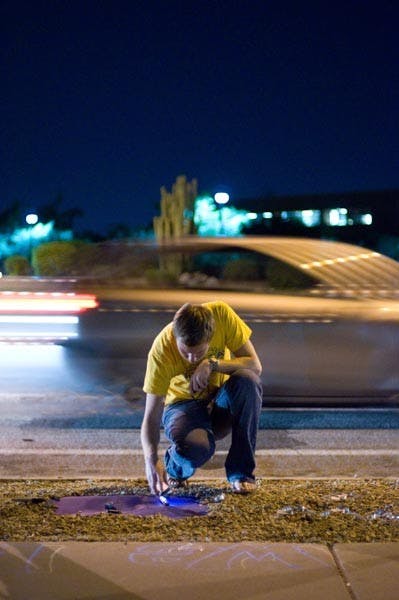 FOR A FRIEND: Bioengineering freshman AJ Stockwell writes a note on the sign in memory of ASU student Matt West. 19 year old West was killed in a motorcycle accident this past weekend. (Photo by Aaron Lavinsky)
