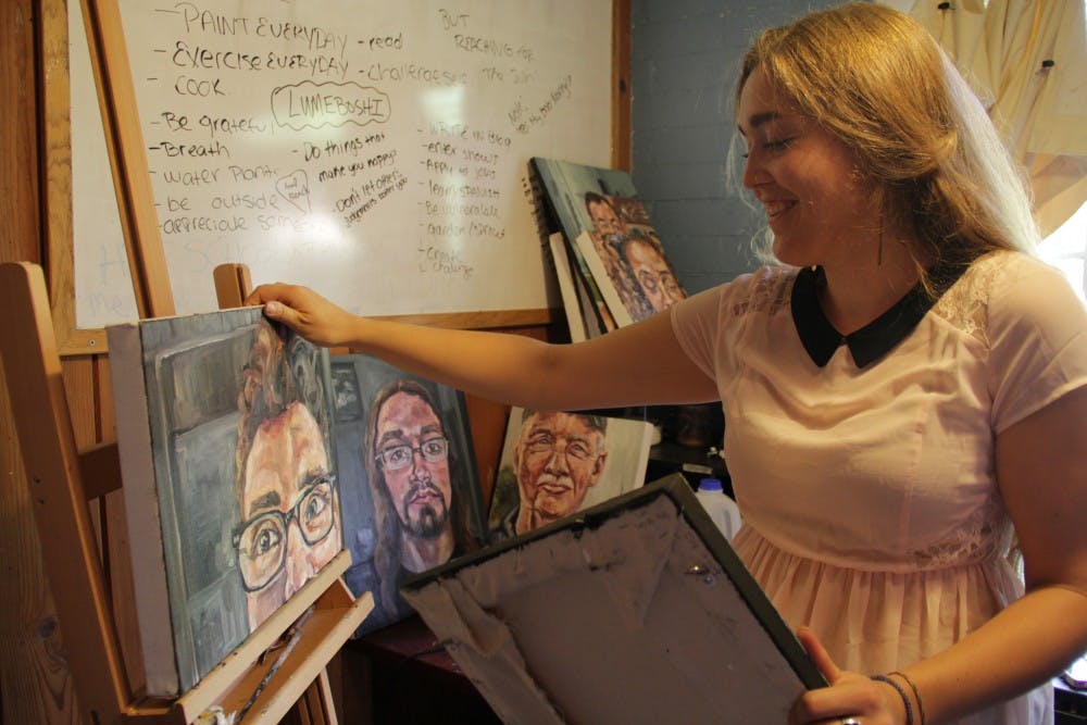 ASU alumna Tasili Epperson shows off some of her paintings in her bedroom, which also serves as her workspace. (Photo by Shawn Raymundo)
