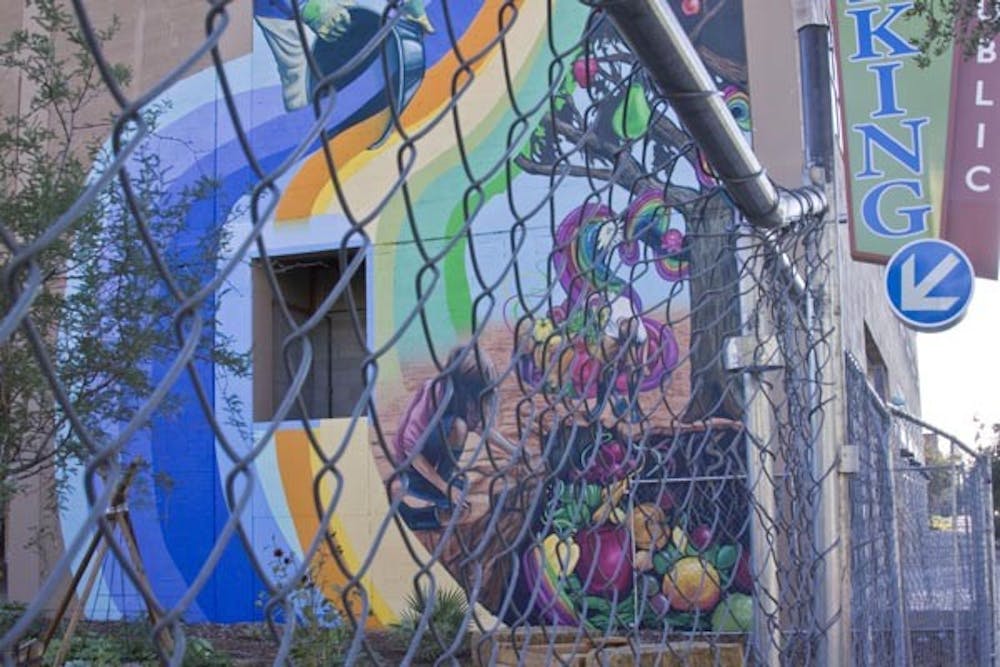 GARDEN ART: A colorful mural peeks through the wires of the fencing surrounding the Urban Garden in Tempe. (Photo by Annie Wechter)