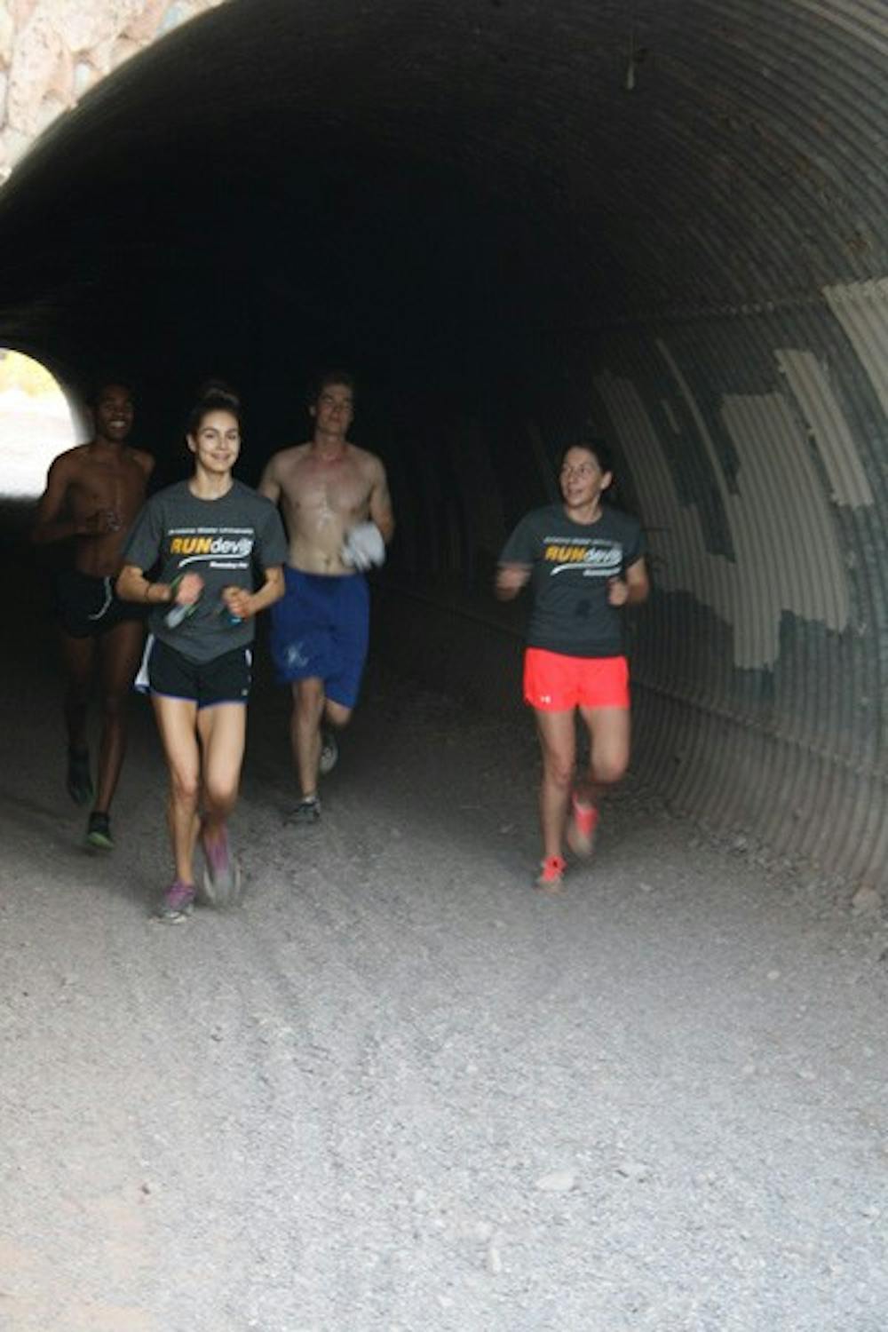 Four members of the ASU Running Club, (left to right) third-year law student Zara Torosyan, computer science sophomore Jack Workman, communications sophomore Emily Glynn, and philosophy senior and club president Daniel Suber emerge out of a tunnel at a local park in Tempe Wednesday morning after running nearly four miles. (Photo by Jessie Wardarski)