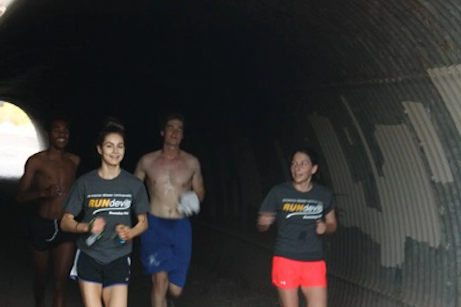 Four members of the ASU Running Club, (left to right) third-year law student Zara Torosyan, computer science sophomore Jack Workman, communications sophomore Emily Glynn, and philosophy senior and club president Daniel Suber emerge out of a tunnel at a local park in Tempe Wednesday morning after running nearly four miles. (Photo by Jessie Wardarski)