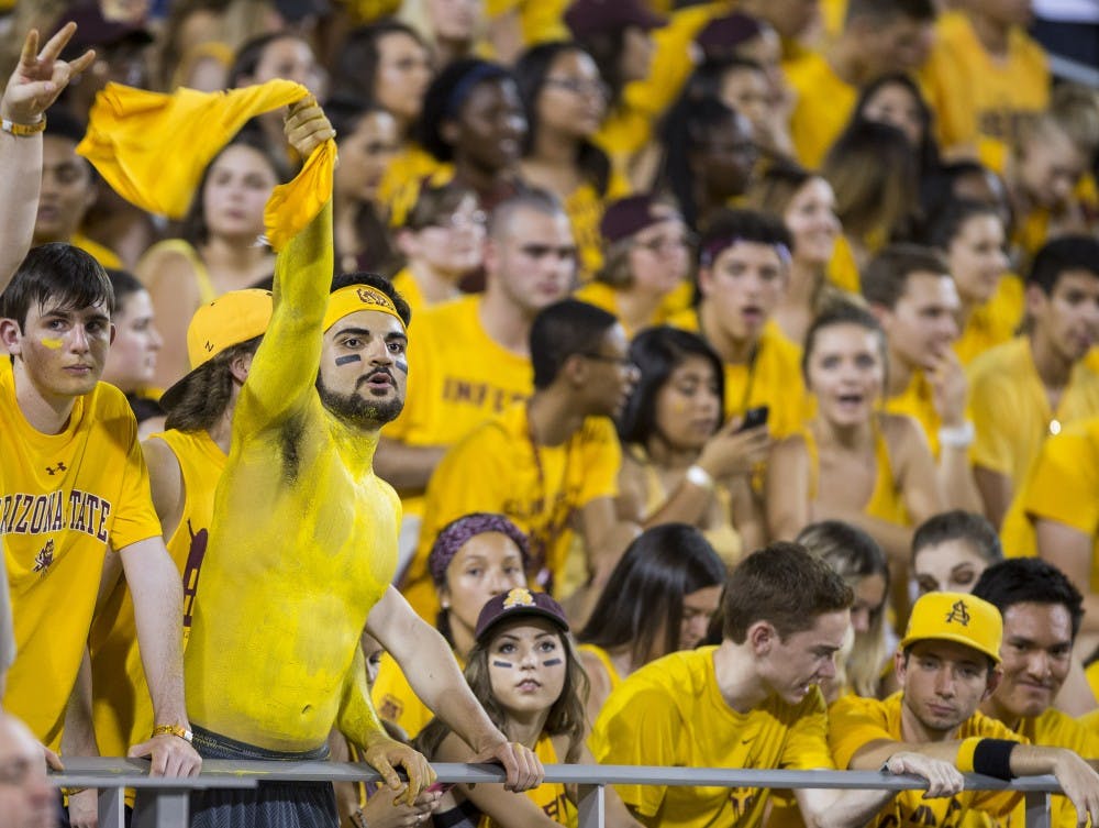 An ASU student covered in gold body paint waves a tee shirt in the south Inferno section during a football game against Cal Poly on Saturday, Sept. 13, 2015. 