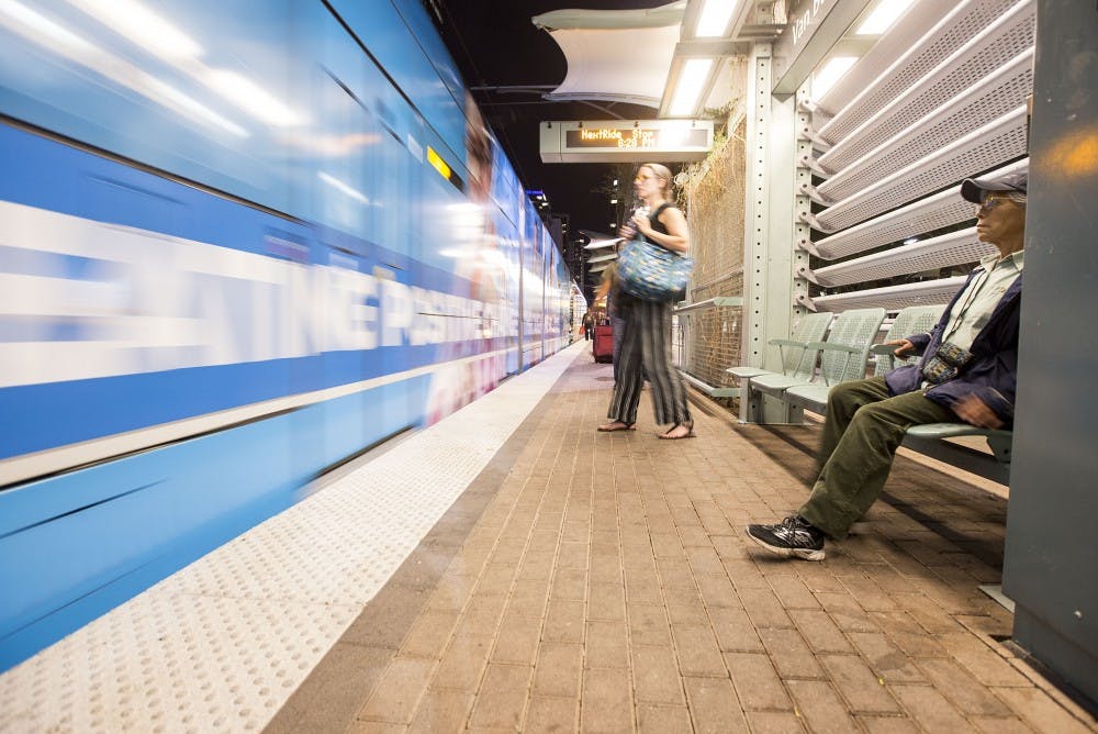 People watch as the light rail pulls into a stop at Washington Street and Central Avenue in downtown Phoenix on Monday, Oct. 31, 2016. 