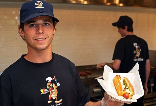 DOGS ON CAMPUS: Dave's Doghouse employee Alex Doyle serves up a Boston Dog, loaded with the signature fixings and stuffed between a garlic toasted bun. The Doghouse on the ASU campus is the second location for Dave's, with the original restaurant located on University St. (Photo by Michael Arellano)