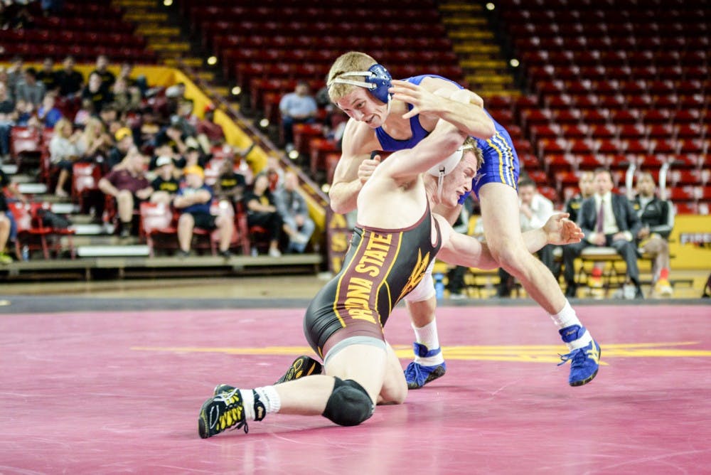 ASU sophomore Oliver Pierce sweeps the leg of CSU Bakersfield's Spencer Hill in their matchup on Sunday, Jan. 18, 2015, at Wells Fargo Arena in Tempe. Pierce won the match 5 – 4. The Sun Devils went on to win against the Roadrunners 31 – 6. (J. Bauer-Leffler/The State Press)