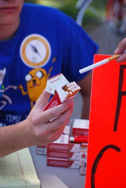 Freshman political science major and member of Students for Liberty Jared Howell hands out a cigarette after a student signs the proposition against the smoking ban on ASU campuses during the Students for Liberty anti-smoking ban protest near the MU on Wednesday afternoon. The ban is scheduled to go in effect next fall. (Photo by Murphy Bannerman)