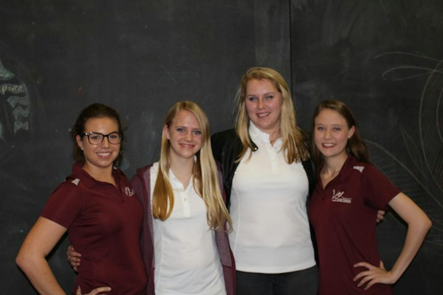 Women in Science and Engineering club members Alex Prassas (left), Kylee Burgess, Halie Bartlowe and Mariah Patton pose in front of a chalk board at The Mesquite Cafe on the Polytechnic campus. The club seeks to promote women in STEM fields. (Bridget Dowd/The State Press)