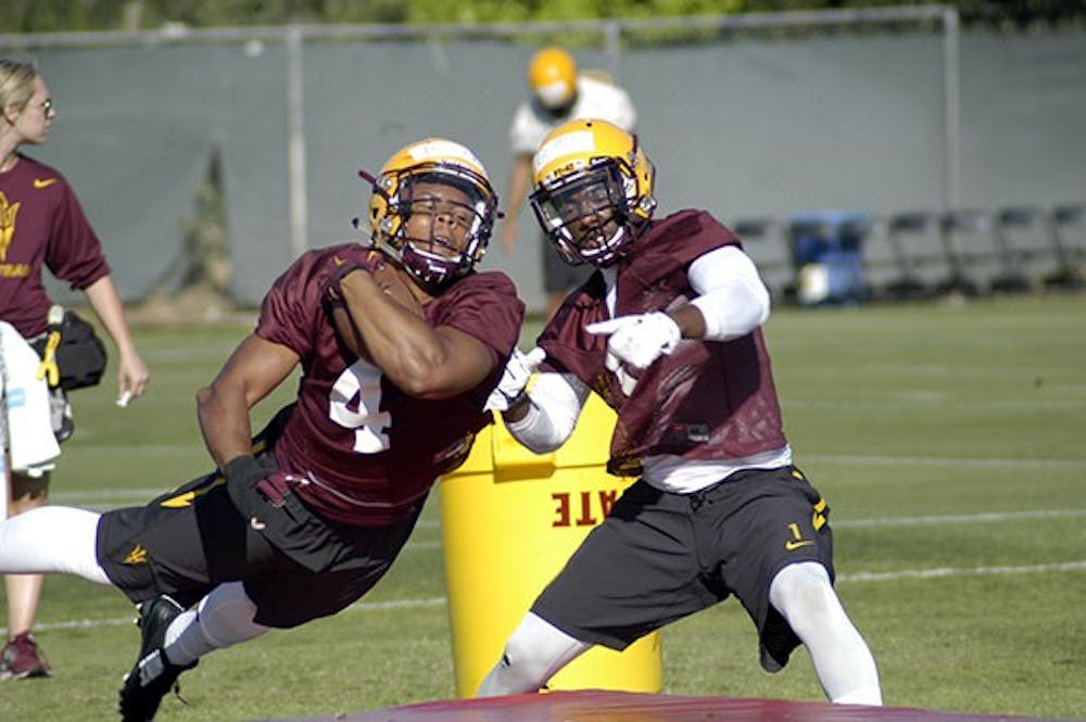 ASU sophomore running back Demario Richard dives forward as redshirt junior running back De'Chavon Hayes tries to strip the football during a drill at spring football practice in Tempe on March 17, 2015. (Fabian Ardaya/The State Press)