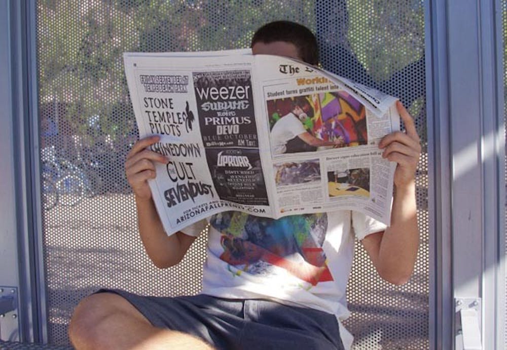 DAILY DOSE: An ASU student catches up on his daily news from The State Press while waiting for the bus Thursday. (Photo by Annie Wechter)