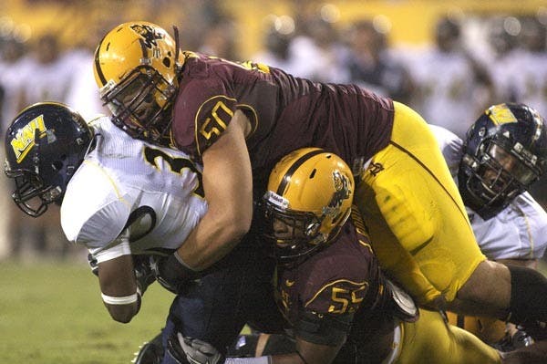 NOWHERE TO RUN: ASU Junior defensive tackle Lawrence Guy (50) and redshirt senior defensive end Jamarr Robinson (55) take down Northern Arizona freshman running back Zach Bauman during last Saturday's 41-20 win. The Sun Devils' defense faces a much bigger challenge on the ground this week in Wisconsin junior running back John Clay, a Heisman Trophy hopeful and the reigning Big Ten Conference offensive player of the year. (Photo by Scott Stuk)