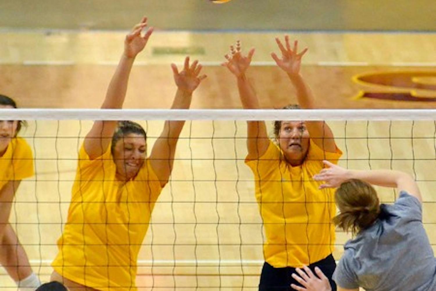 BUILDING BLOCKS: ASU senior middle blocker Sonja Markanovich and redshirt sophomore outside hitter Ashley Kastl raise up to block a shot in the Alumnae Match last August. The team centers on their unofficial motto, “One and Done,” to encourage themselves during games. (Photo by Aaron Lavinsky)