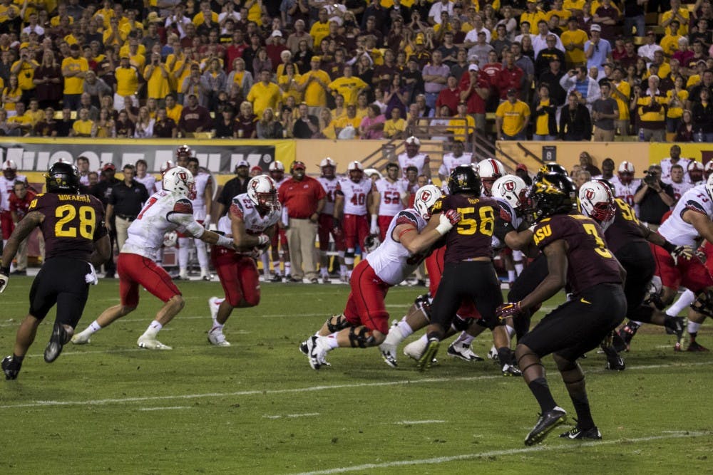 Utah junior quarterback Travis Wilson hands off the ball to junior running back Devontae Booker in a game against ASU in Tempe on Saturday, Nov. 1, 2014. ASU won against Utah 19-16. (Photo by Alexis Macklin)