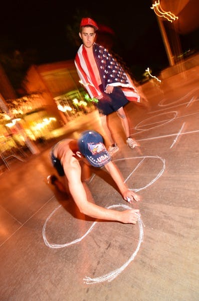 GOT HIM: Aeronautical management sophomore James White (right) and political science sophomore Steven Pizzi write patriotic slogans with chalk outside of the Memorial Union on Sunday night after hearing that the leader of al-Qaida, Osama bin Laden, was killed during a raid by the Navy Seals. (Photo by Aaron Lavinsky)