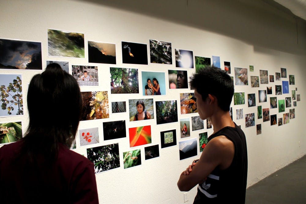 Art students look at photos in the Rio Canción exhibit hosted by Guarama. The nonprofit organization helps low-income students in Honduras. 