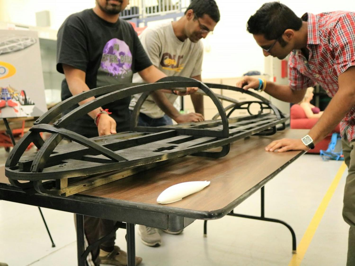 Members of the AZloop manufacturing team work with a display model of the pod at ASU's Polytechnic campus on Friday, April 7, 2017.