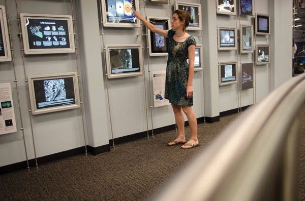 Planetary sciences graduate student Sarah Braden points to a video monitor displaying photos of a lunar volcanic crater on Thursday in the visitor gallery of the ISTB A building on the Tempe campus. (Photo by Aaron Lavinsky)