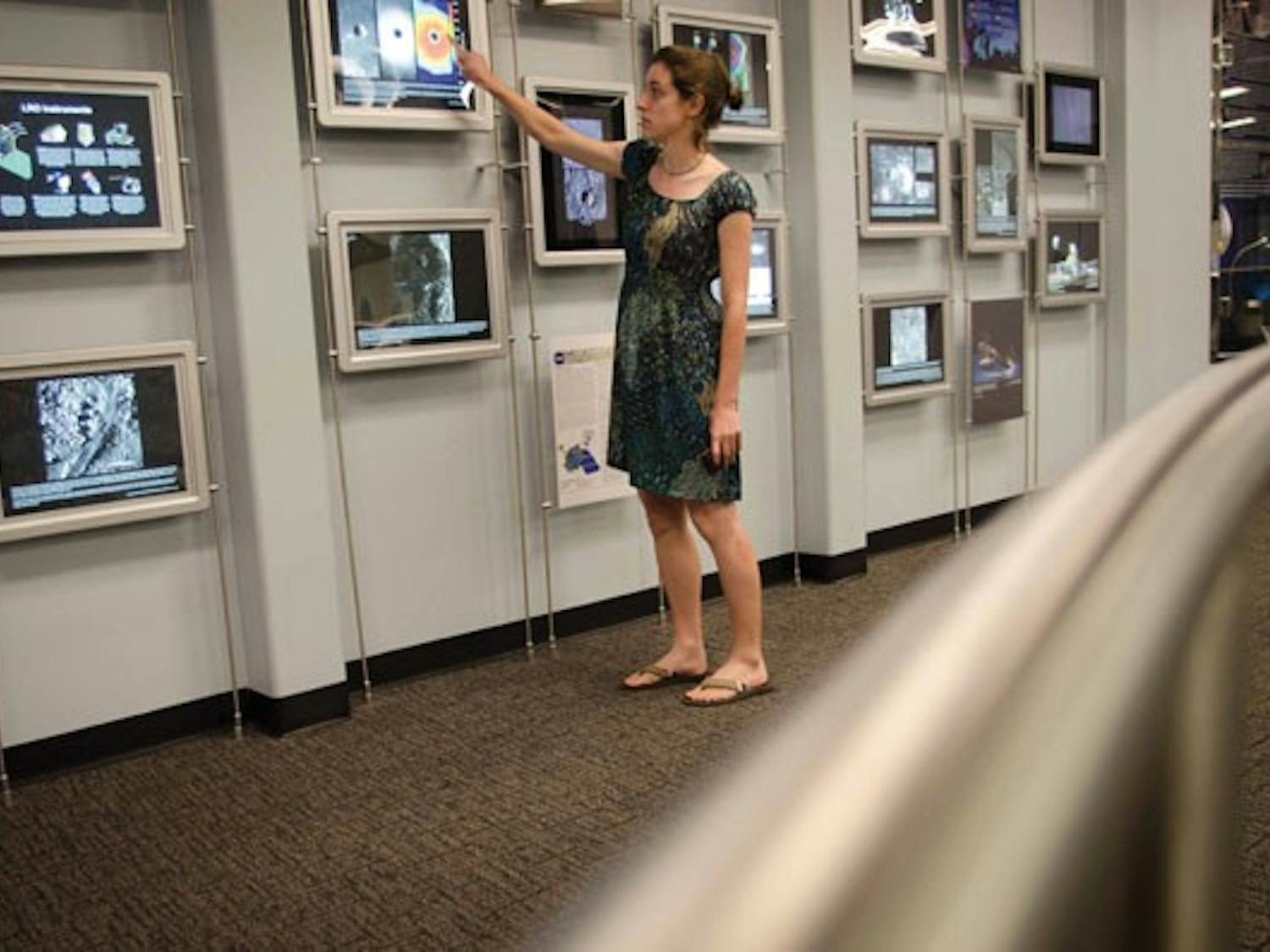 Planetary sciences graduate student Sarah Braden points to a video monitor displaying photos of a lunar volcanic crater on Thursday in the visitor gallery of the ISTB A building on the Tempe campus. (Photo by Aaron Lavinsky)